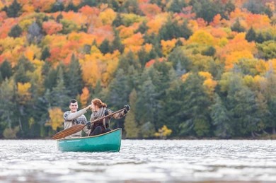 “Couple canoeing on a lake with colorful autumn foliage in Canada”
